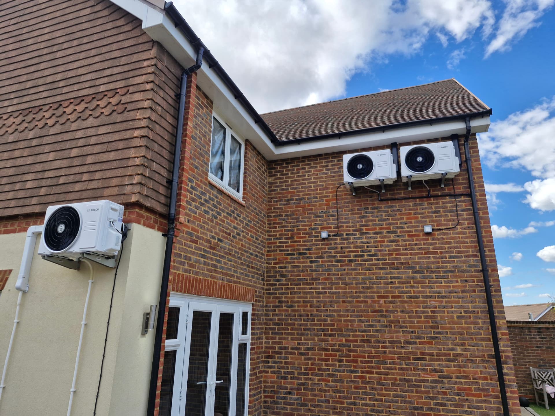 Three external air conditioning condenser units mounted on a house